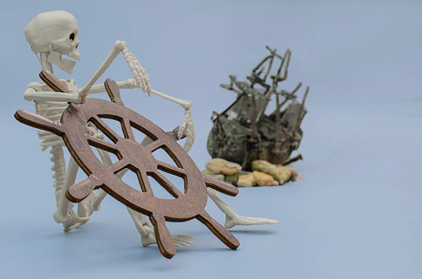 A conceptual still life featuring a model human skeleton holding a wooden helm with a blurred shipwreck in the background, ghost stories, and lost voyages.