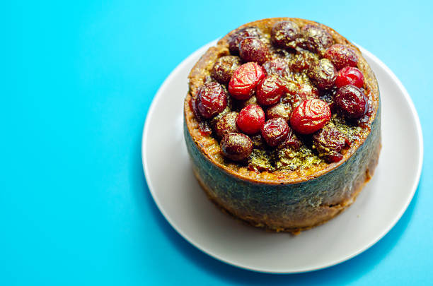 A small cake with berries on top of it. The cake is on a plate and is sitting on a table