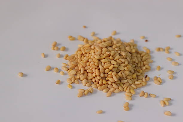 Fresh organic pine nuts in a small bowl shot from above on rustic wooden table. Healthy food ingredient or snack