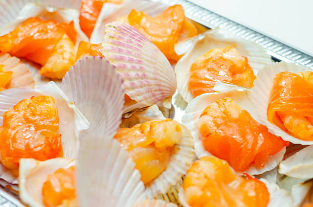 A tray of shrimp is covered in shell cups. The shrimp are orange and arranged in a pattern
