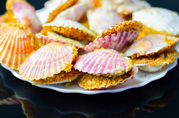 A plate of food with shells on it. The shells are pink and white. The plate is on a black background