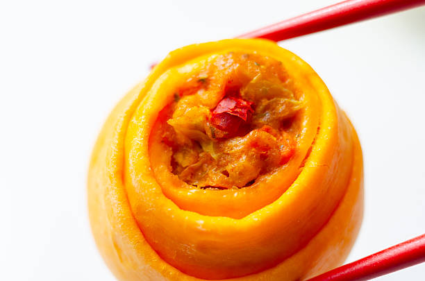 A piece of food with a red star on it. The food is orange and is being held by chopsticks