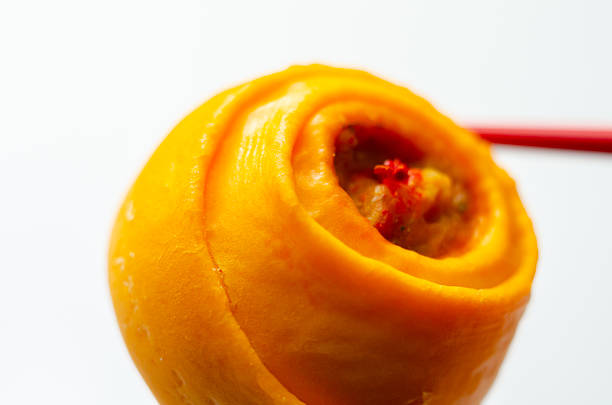 A piece of food with a red star on it. The food is orange and is being held by chopsticks