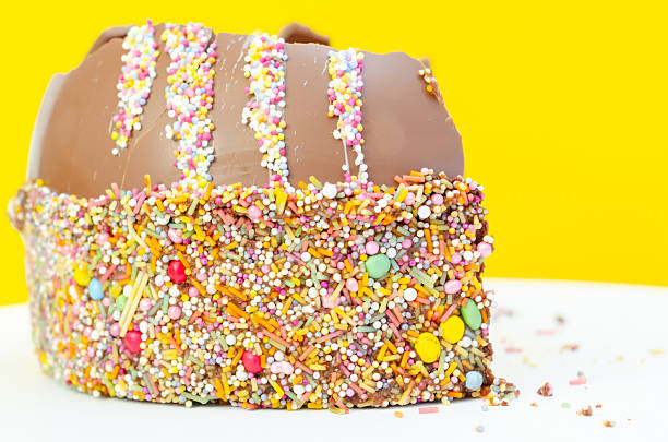 A chocolate cake with colorful sprinkles on top. The cake is cut in half, revealing a chocolate filling