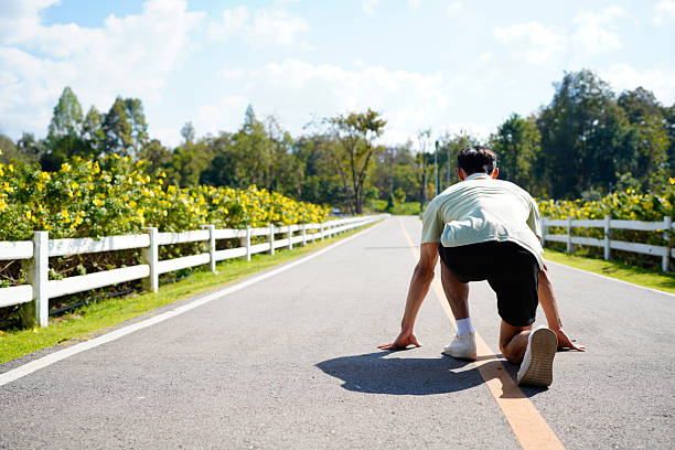 Smiling active man standing in start position, jogging running and walking doing fitness in the park.