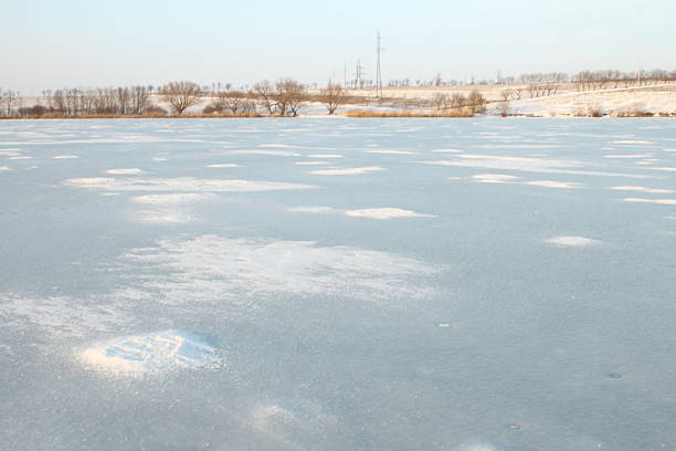 A snowy field with a few trees. Outdoor. Sky. Nature. Shore. Day