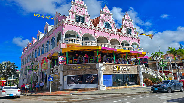 Oranjestad, Aruba. May 23rd, 2009: Colorful waterfront view of the Royal Plaza Mall along the harbor of Oranjestad, with small boats moored in the turquoise Caribbean Sea under bright tropical skies.