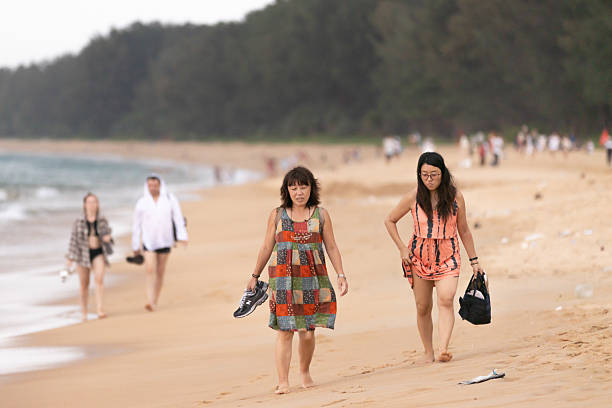 14 November 2025, Phuket Island - Thailand.Asian tourists are walking on Mai Khao beach.The area is less crowded than many other beaches in Phuket.