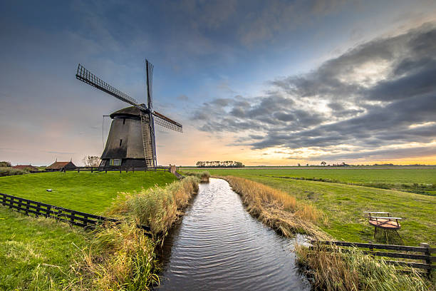 Three Traditional wooden windmills along canal in old agricultural landscape near Schermerhorn, North Holland. Netherlands