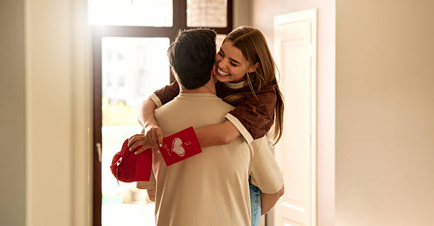 Couple exchanging heart shaped gift box on Valentine's Day, top view