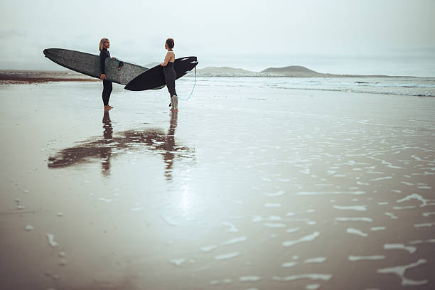 istock Female Surfers Talking on Reflective Beach Before Surfing 2255725519