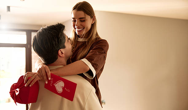 Couple exchanging heart shaped gift box on Valentine's Day, top view