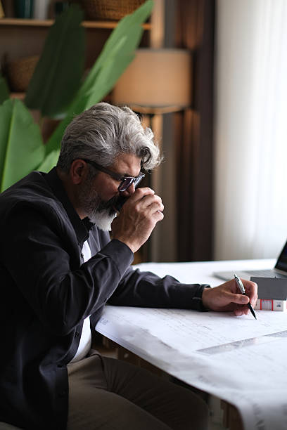 istock Architect designing a new project using a ruler and pencil with laptop 2255728455