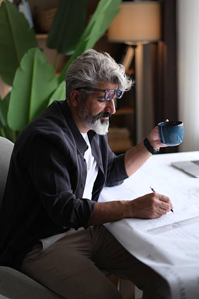 istock Architect man holding pencil working with laptop and blueprints for architectural plan, engineer sketching a construction project concept. 2255728541