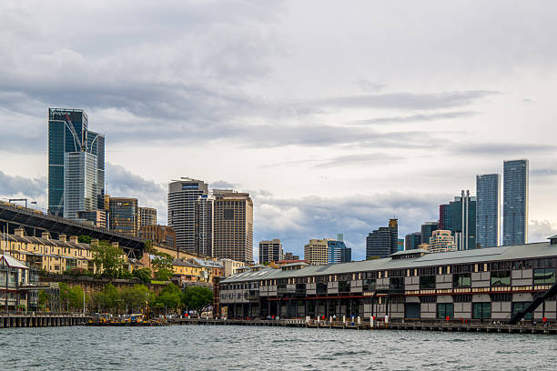The Sydney Harbor skyline with tall skyscrapers on a cloudy day.