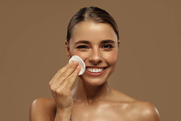 istock Beautiful woman smiling while cleansing her face with cotton pad 2255734033