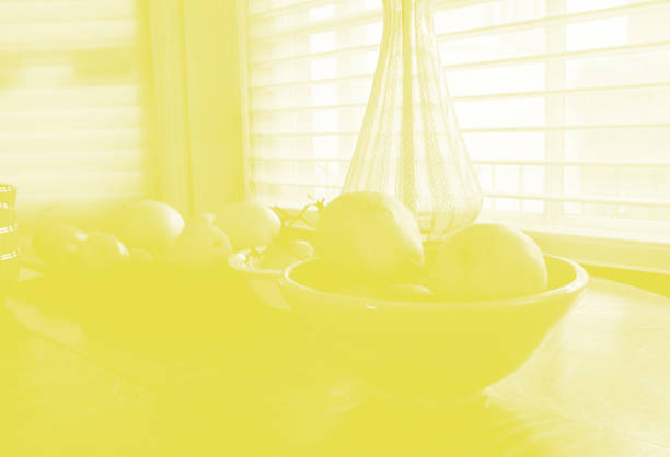 Yellow monotone image of kitchen table with fruit and lamp with copy space. 35mm Film.