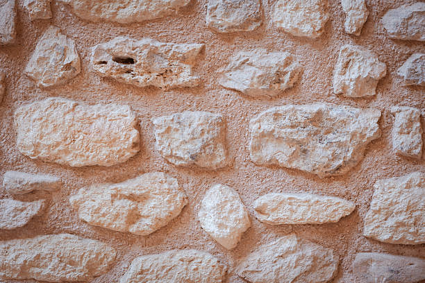 Rustic stone wall forming an ancient architectural background, creating a textured surface ideal for historical building designs and natural material themes, symbolizing strength and durability