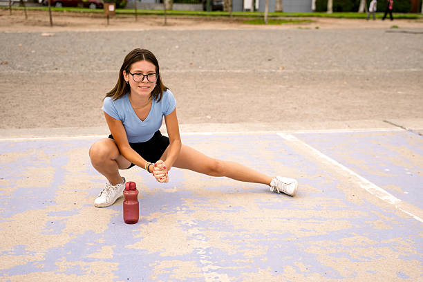 Young woman stretching and warming up for her workout in an urban park. Focus on fitness, wellness, and healthy lifestyle