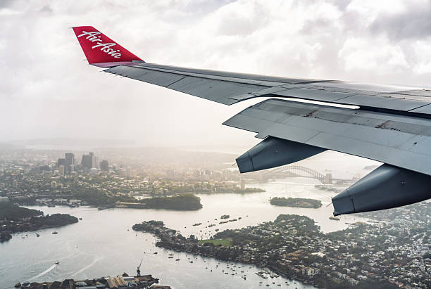 Sydney, Australia - Air Asia's logo on the wingtip of a plane as it passes Sydney Harbour and the city's CBD.