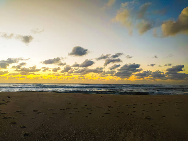 Stunning golden sunset over a tranquil beach with footprints in the sand. This serene coastal landscape evokes peace and adventure, perfect for travel, wellness, and motivational themes.