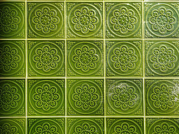 Elegant green ceramic tiles with embossed floral patterns create a vintage architectural texture. Ideal for interior design, backgrounds, and decorative projects seeking a classic touch.