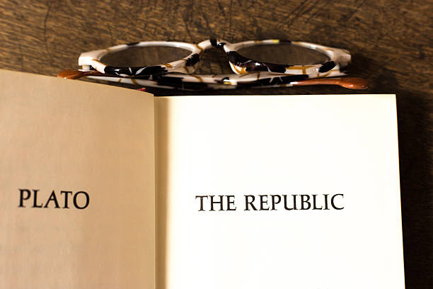 Open Book, Title Page: Republic by Plato. Brown wood desk background, with glasses.