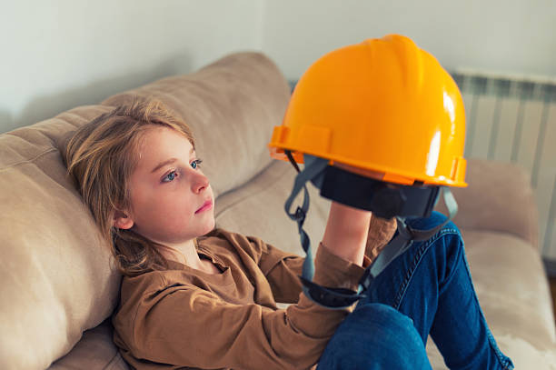 Cute little boy putting on a safety helmet before riding a scooter or bike. Outdoor summer activities for children