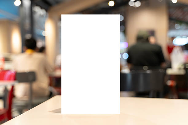 Vertical blank white card on a table in a modern cafe, shallow depth of field with people and warm lights blurred behind. Perfect for menu, signage, branding, template and copy space.