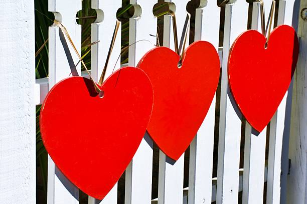 istock Red Painted Wood Hearts on a White Painted Fence 2255803454