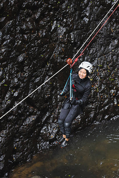 High Angle Shot Of Smiling Muslim Woman In Hijab And Helmet Zip Lining Across River During Canyoning Adventure