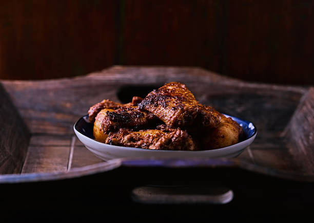 Macro photography of a roasted chicken leg with a single green olive on top