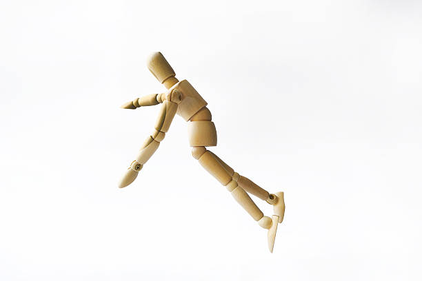 A wooden mannequin in a dynamic pose, demonstrating movement or falling. The figurine is executed in light colors and features articulated joints, highlighting its flexibility and design