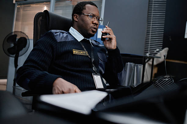 istock Middle Aged Black Man Working as Security Guard Using Walkie Talkie Indoors 2255819380