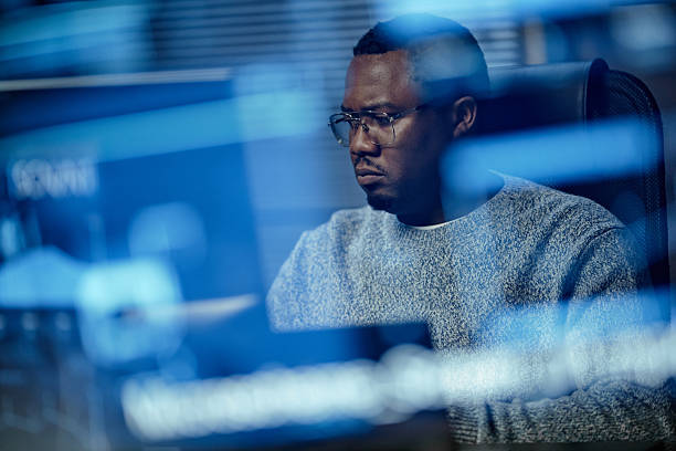 istock Young Adult Black Man Concentrating While Reviewing Security Data on Computer 2255822474