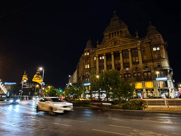 Traffic on the street at night by the Anker Palace, a building in Terézváros, Budapest. The building was built in the eclectic style and was completed in 1910.