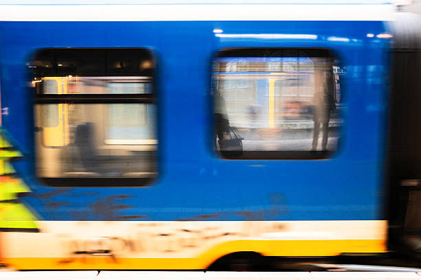 The Netherlands. A Dutch NS Sprinter train rushes past at high speed, captured with a long shutter speed creating strong motion blur. The characteristic blue and yellow colors blend into abstract streaks, conveying speed, movement, and modern rail transport in the Netherlands.