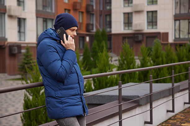 istock Man in winter jacket having phone conversation outdoors 2255837647