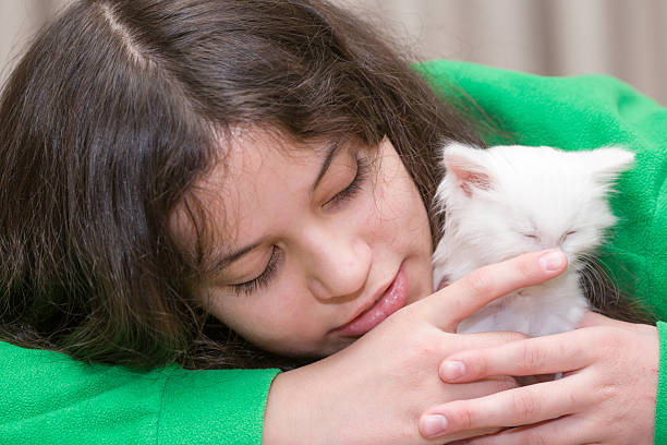 Russia. The lives of ordinary people. A teenage European girl plays with a white kitten.