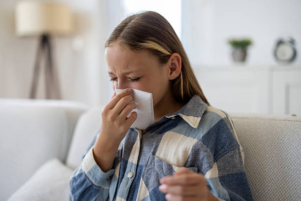 istock Sick girl holding tissue while sitting on sofa at home 2255842037
