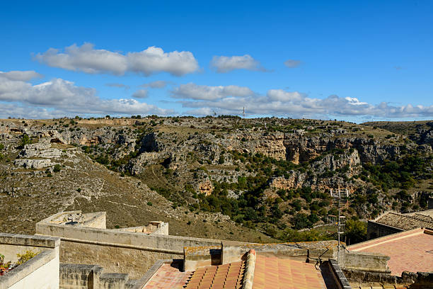 Italy, Matera - May 22, 2024: Panoramic view from Luigi Guerricchio Belvedere of historic city carved in rock Sassi of Matera. Bell tower of Matera Cathedral in a distance