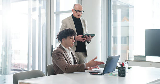 istock Collaboration, laptop and tablet with business people in office for development or feedback. App, review or technology with boss and corporate employee at desk in workplace for project management 2255847593
