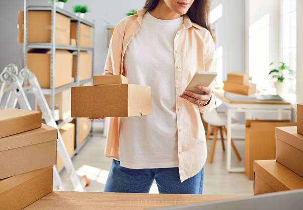 istock Internet store owner or inventory manager preparing parcels and using mobile phone 2255850686