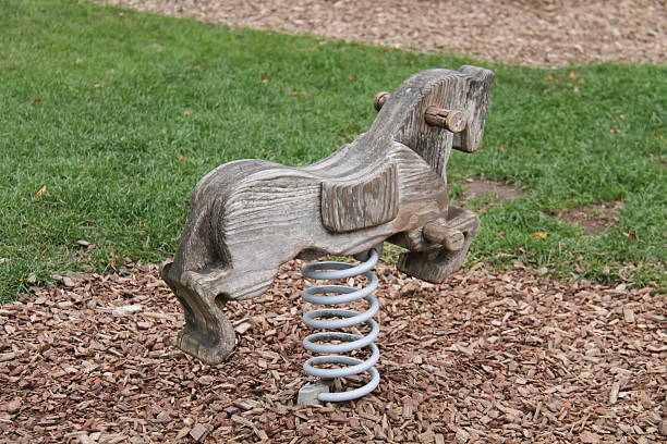 Wooden horse chariot in sunlit playground by tranquil lake.