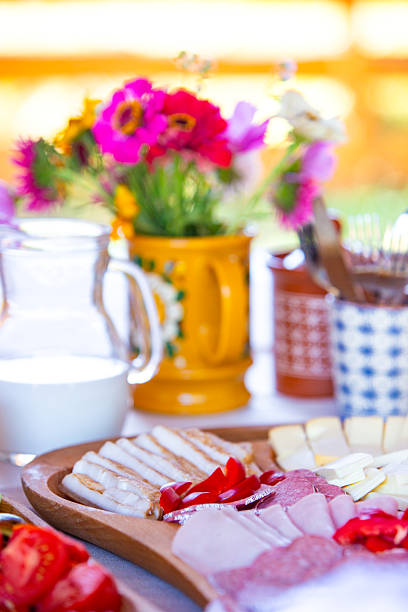 Brightly colored breakfast table with cheese, vegetables, and flowers in natural lighting.
