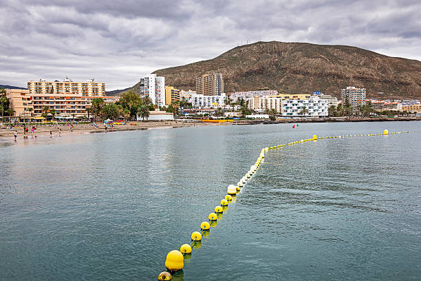 Los Christianos, Tenerife, Spain, Europe - December 19th 2025: A view of the historic town on the south coast of Tenerife, where the harbour and the beach are situated next to each other. The area is part of one of the island’s long‑established tourist zones, supported by a professional tourism industry that has operated for many years.