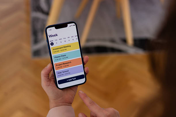 istock Person holding phone managing week schedule on app 2255863839