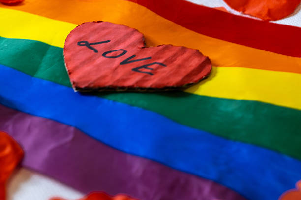 Handcrafted heart with love written on it laying on a vibrant rainbow pride flag