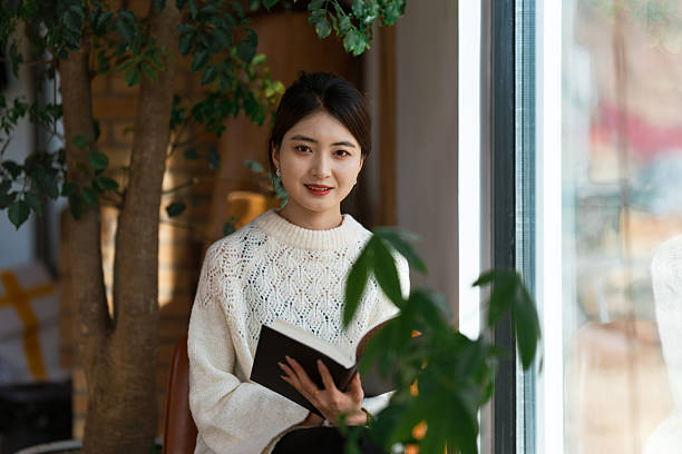 istock Young woman is reading book by the window 2255871339