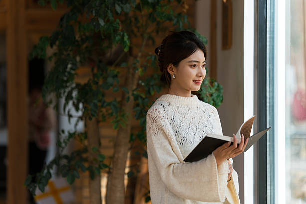 istock Young woman is reading book by the window 2255871536